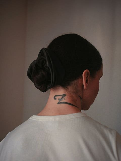 Chignon bas noué sur la nuque avec un ruban de satin noir, vu de dos